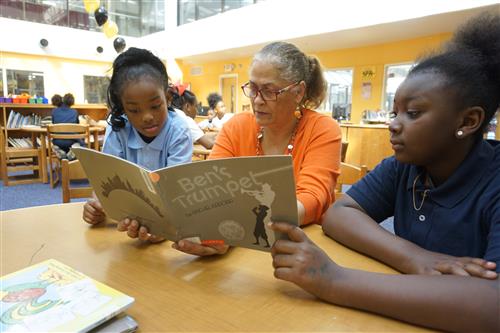 Students reading with a teacher 